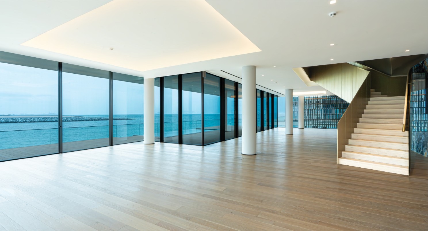 Open-plan living space with floor-to-ceiling glass onto the sea