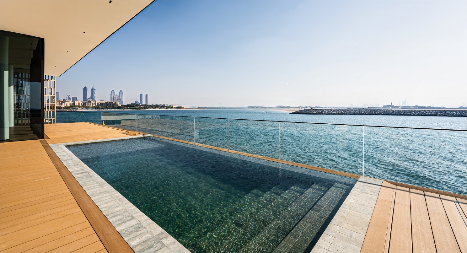 Deck pool at the water's edge with the Dubai skyline beyond